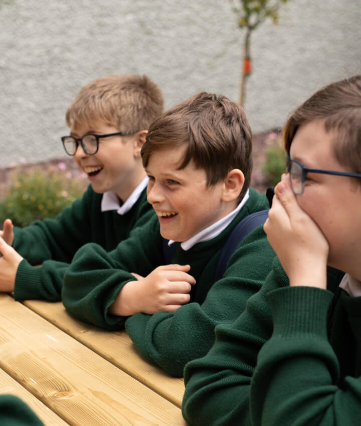Three post primary school students in green uniform laughing together outside