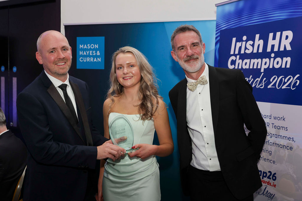 Three people posing at the Irish HR Champion Awards 2026 in The Marker Hotel, Dublin, during the presentation of the Champion Learning & Development Programme Award. A man in a black tuxedo presents the award trophy to a woman in a light green dress, while another man in formal attire stands beside them. Event branding for the Irish HR Champion Awards 2026 and Mason Hayes & Curran is visible in the background.