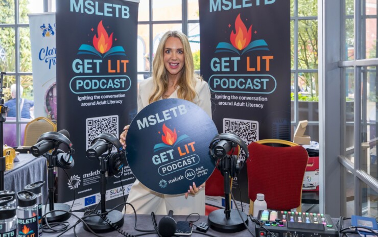 One woman standing on front of podcast equipment.