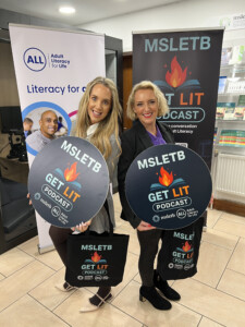 Two women, side by side with both holding a circular sign that reads "MSLETB Get Lit Podcast".